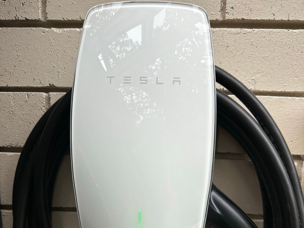 Tesla Wall Connector EV charger installed on exterior brick wall