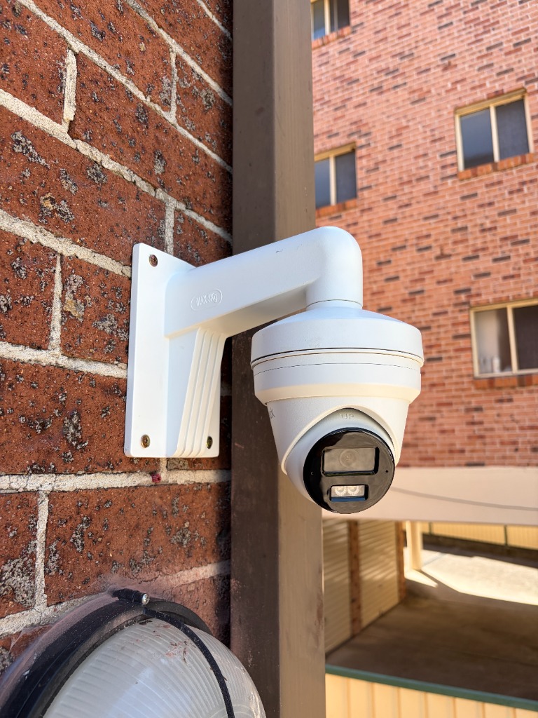 Commercial turret CCTV security camera wall-mounted on brick building